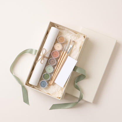 Open gift box with rolled canvas, numbered paints, brushes and a blank card